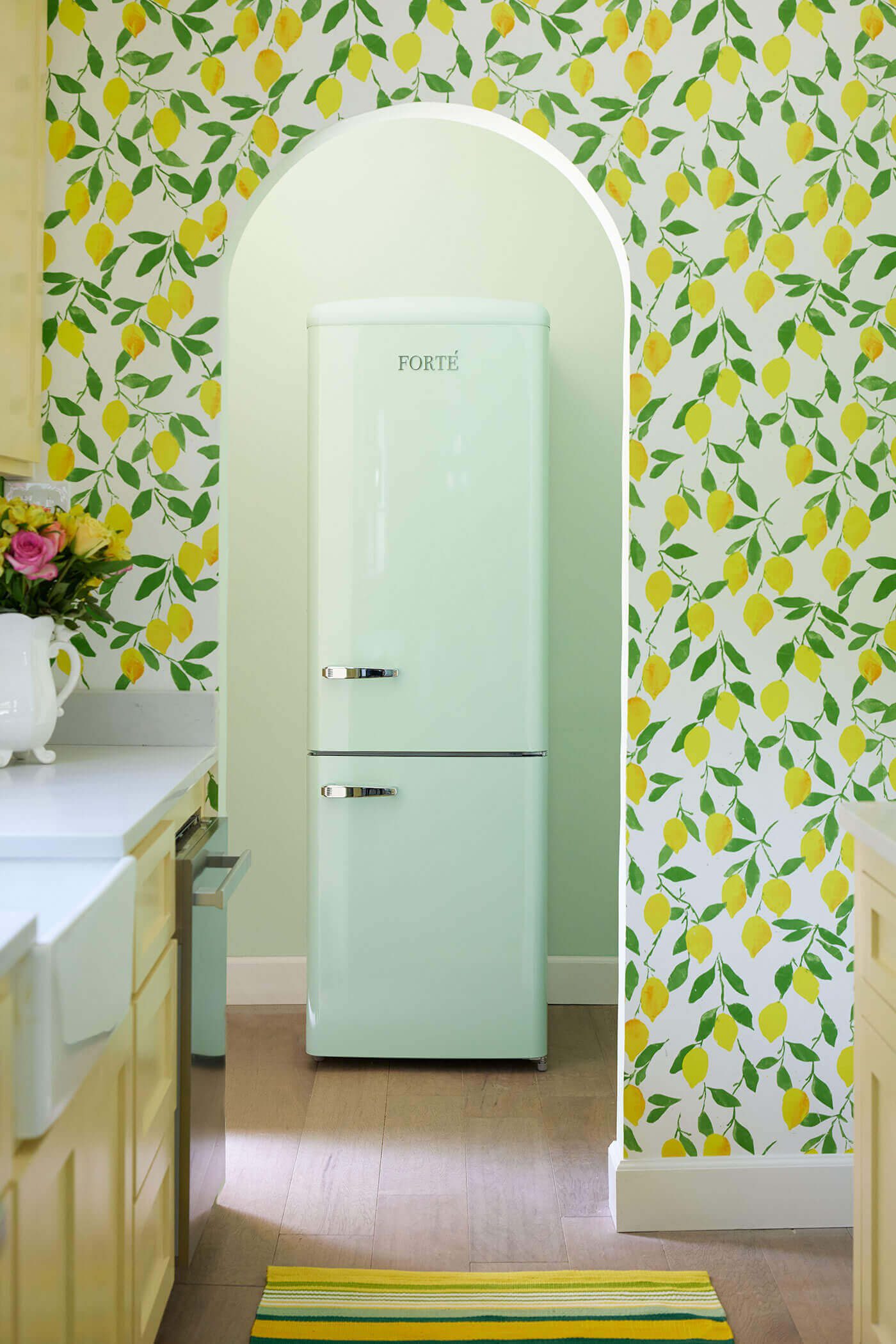 Wallpapered wall with archway entrance and retro fridge through archway