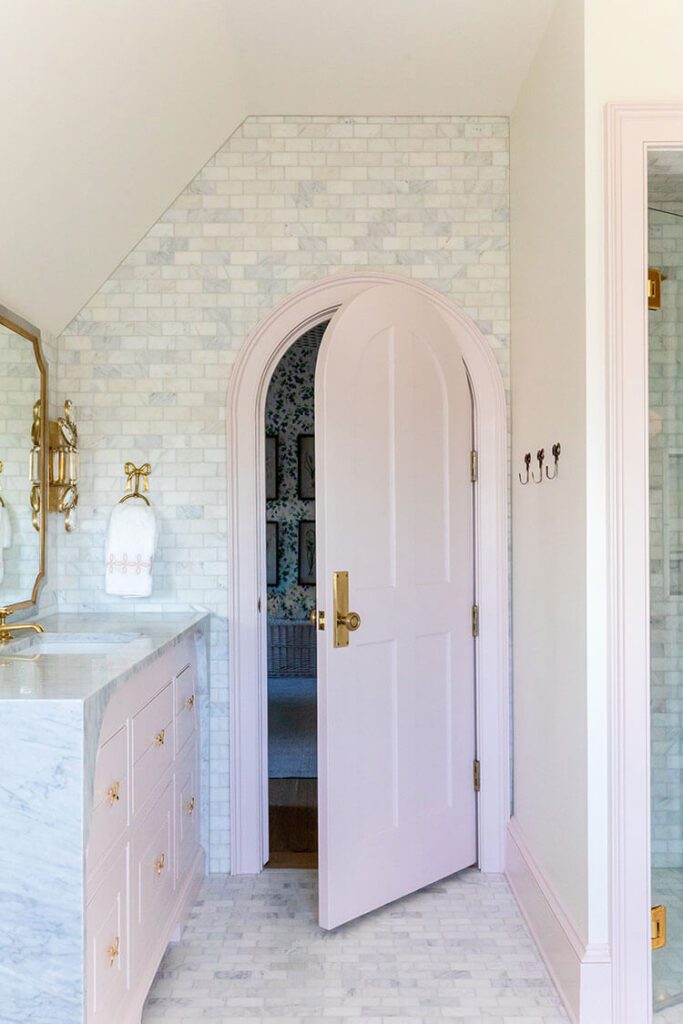 Bathroom with pale pink door and an arched doorway, for interior design trends of 2023
