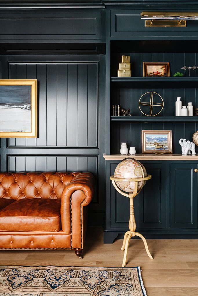 Dark wood painted home office with blue walls and leather sofa