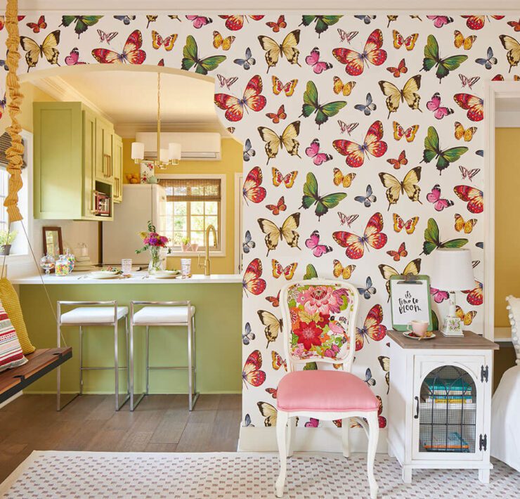 Bedroom looking into kitchen, with bright butterfly wallpaper