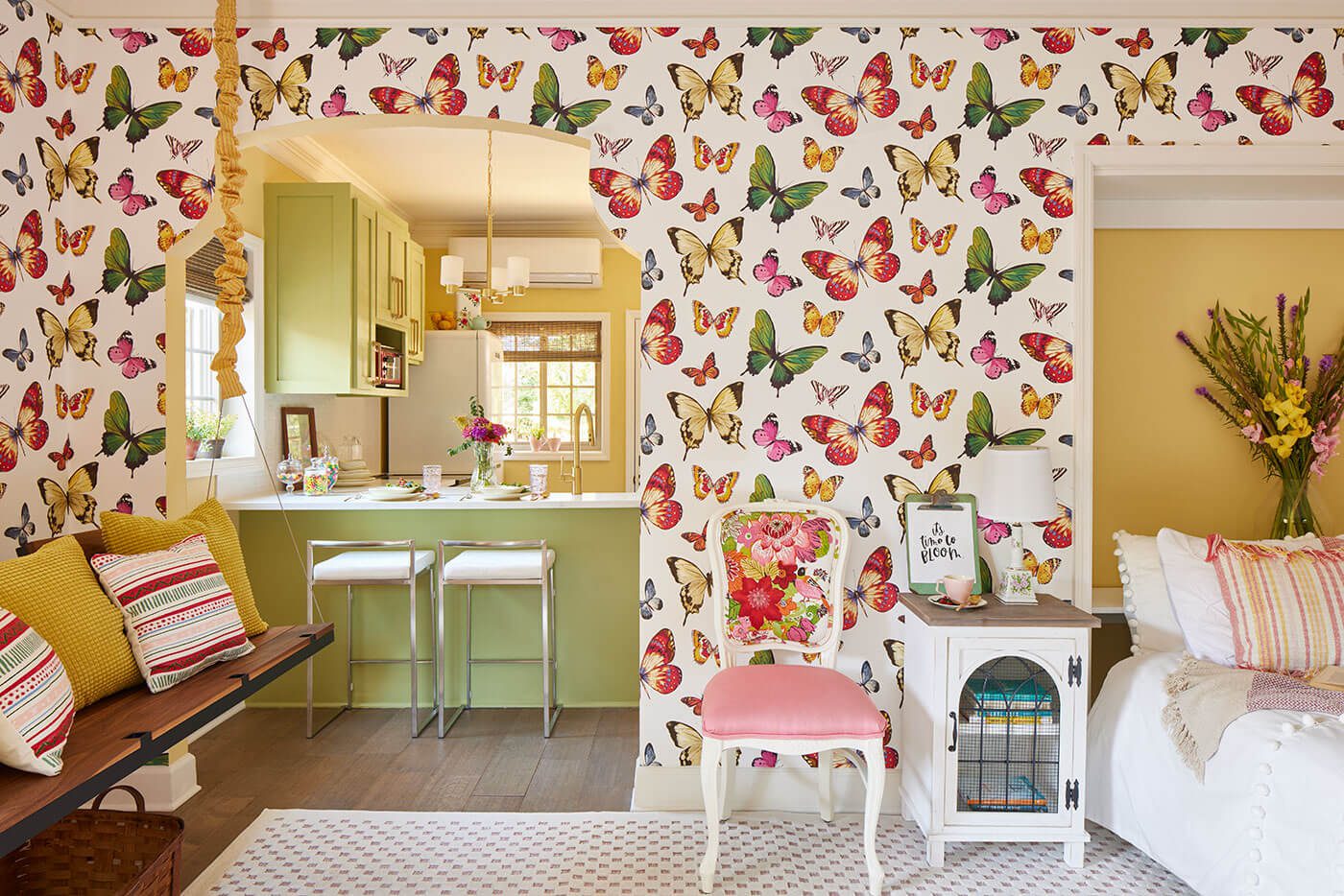 Bedroom looking into kitchen, with bright butterfly wallpaper