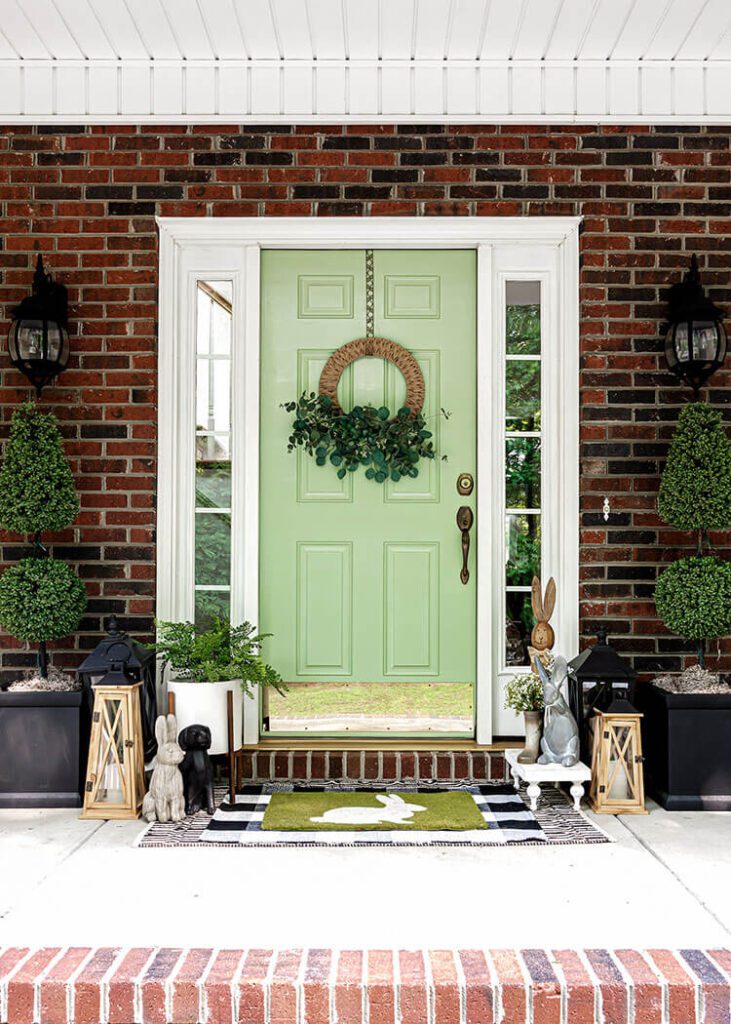 Front door with green paint and outdoor spring decorating around the edges