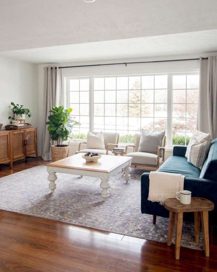 A mostly white interior has an MCM style blue velvet chair with plenty of wood accents peppered throughout the room.