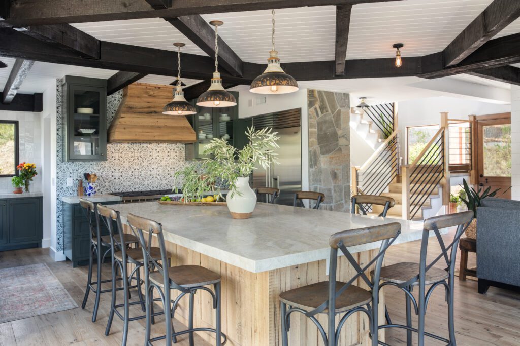 A view of the kitchen with shaker style painted green with blue and white terracotta tile under a wood range hood.