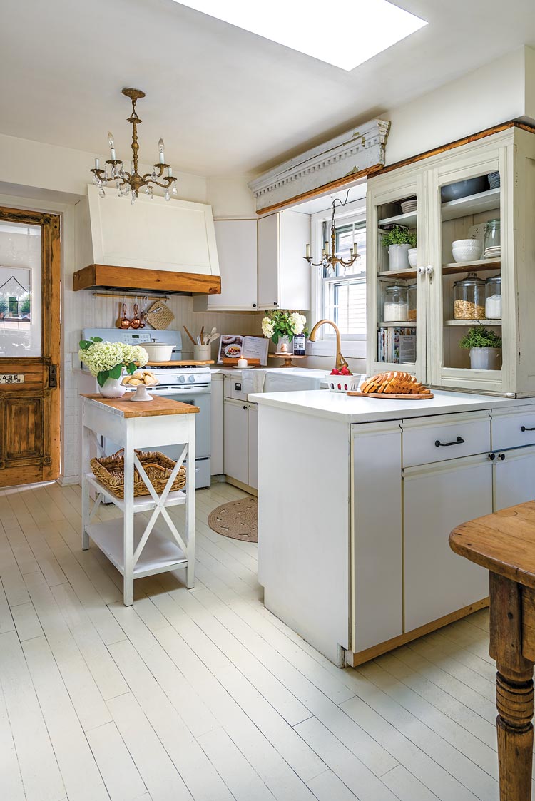 white kitchen with vintage chandelier and wood edged oven hood