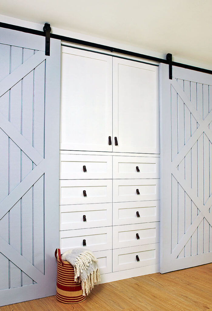 Hidden cabinets covered by blue barn doors with leather drawer pulls