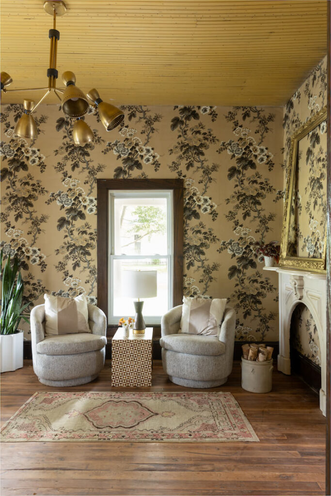 sitting area with floral wallpaper and large vintage frame on mantel