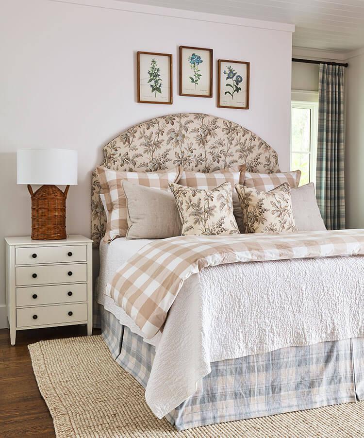 Floral and plaid bedding making the guestroom feel welcoming to all guests. The colors are in muted tones of soft pinks and blues.
