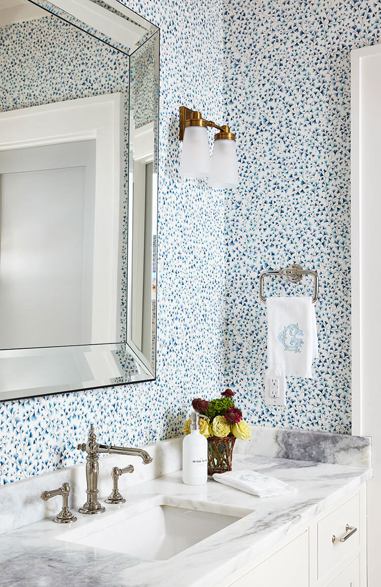 The wallpaper of this guest bathroom is covered in tiny blueish green maindenhair ferns that grow in the area.