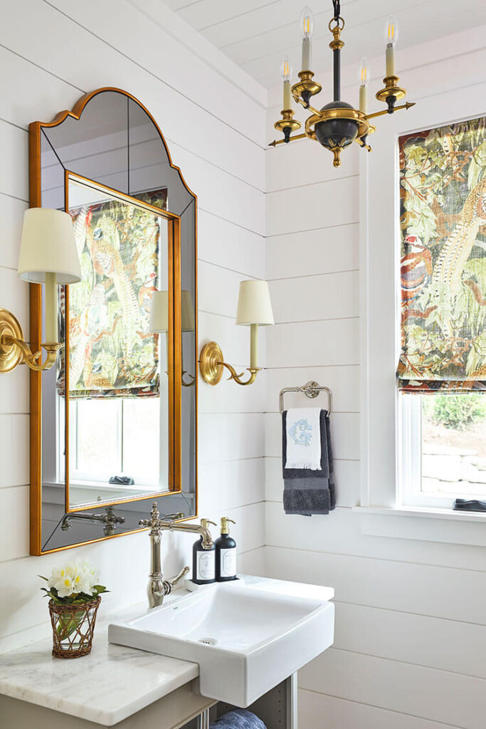 A white shiplap powder room gets unique finishes and high-quality features including a small apron style sink.