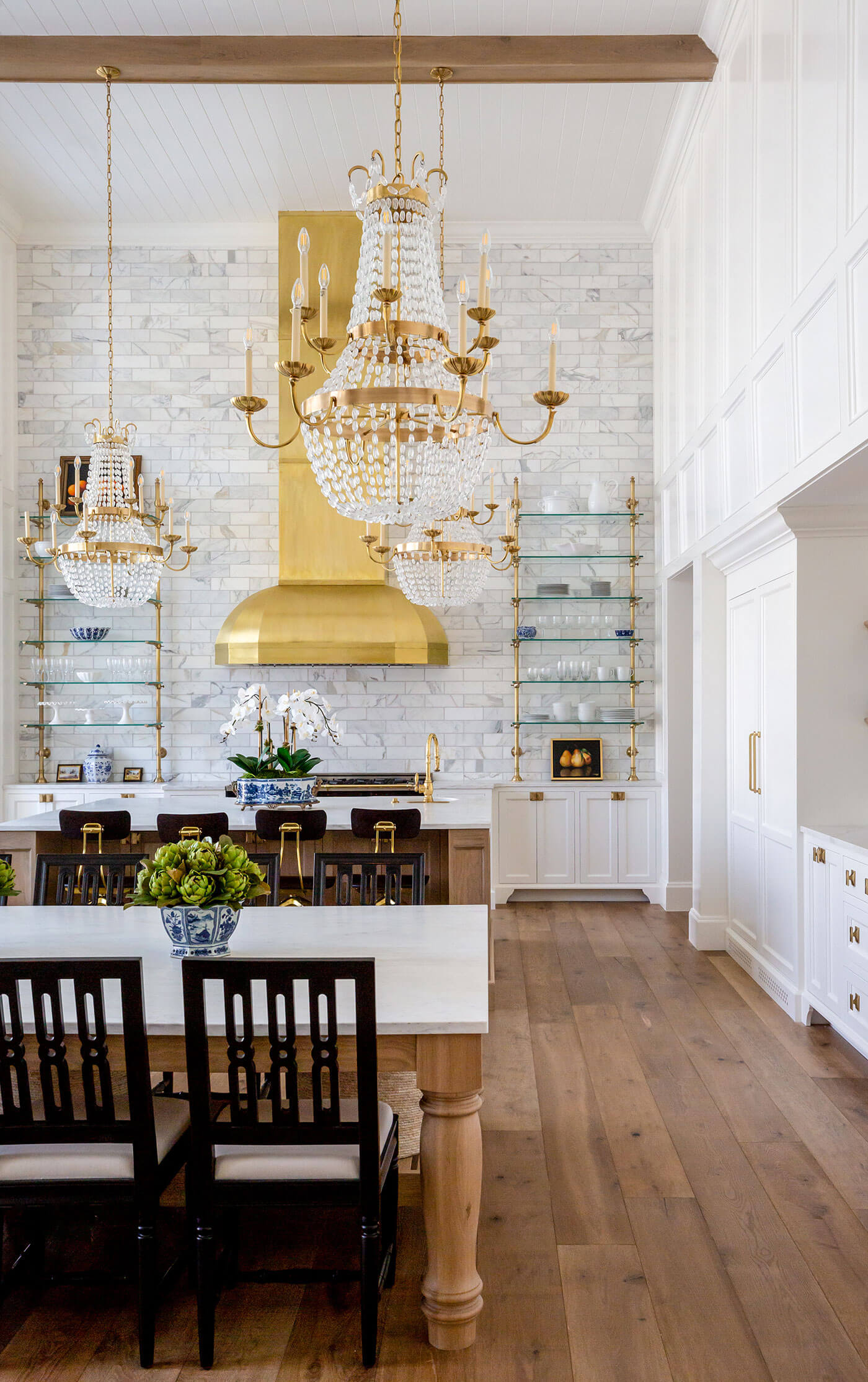 Inside beautiful kitchen with two stories, large chandeliers and tall backsplash
