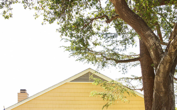 Exterior of yellow farmhouse with cute front porch and blue door