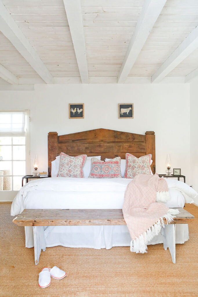 Bedroom with coastal farmhouse style, white bedding and wood head board