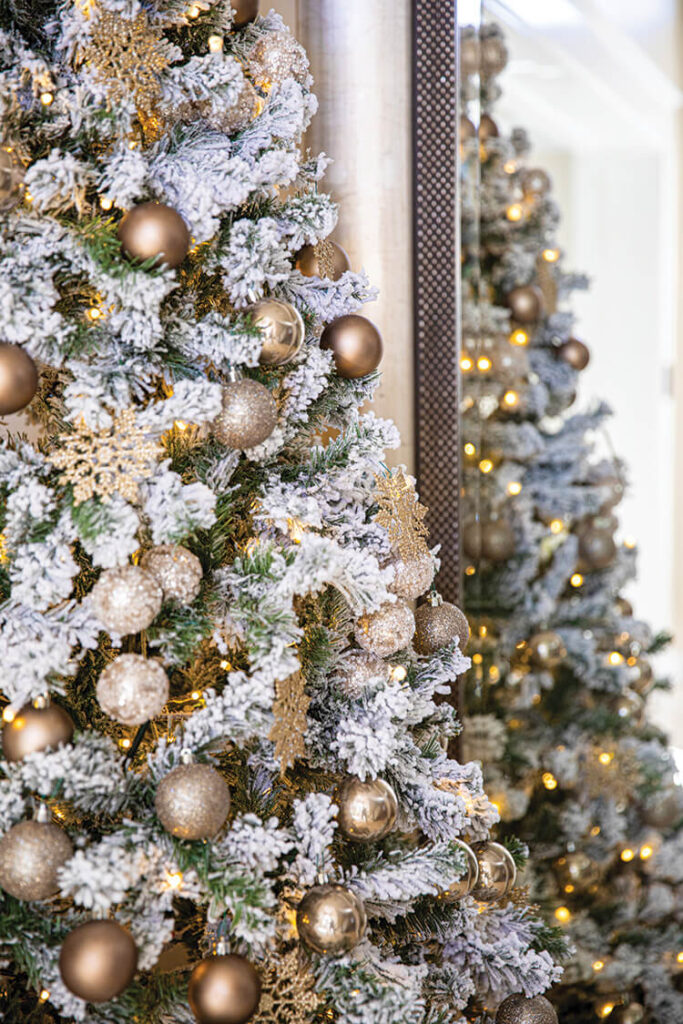 flocked Christmas tree in entryway with gold ornaments