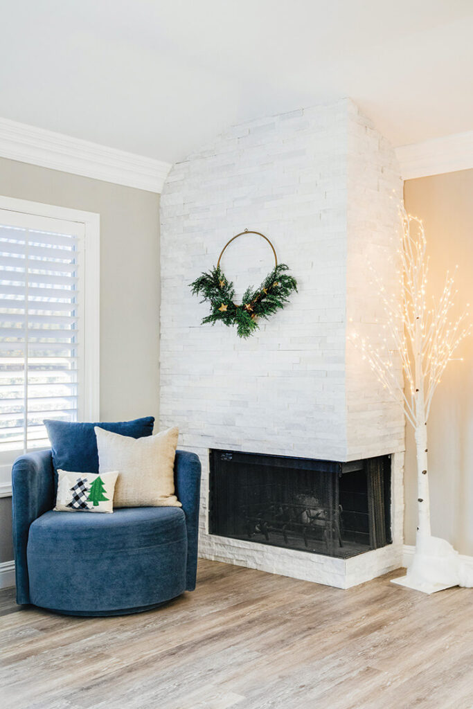 faux birch tree with lights and simple wreath on fireplace wall