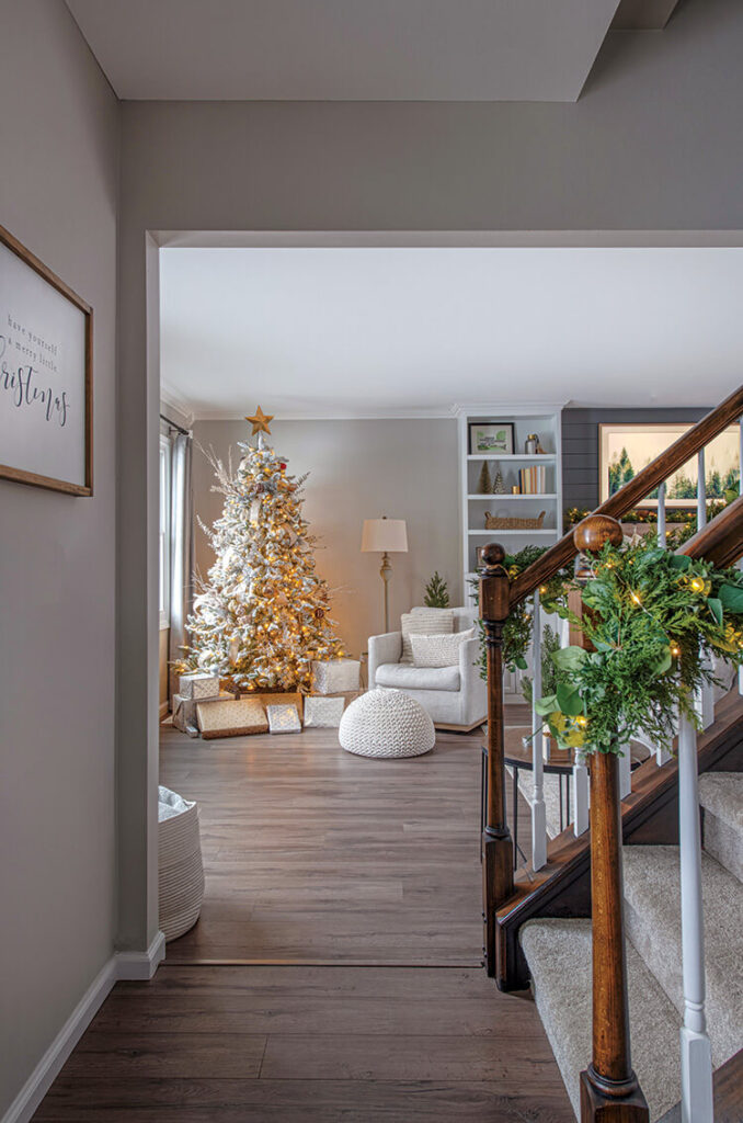 garland on staircase with view to living room Christmas tree