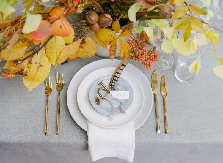 A view of the table setting that includes two forks and two knives, all in gold to juxtopose with the white plates and table cloth