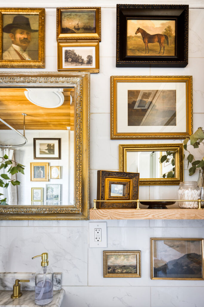 Vintage-inspired gallery wall in bathroom with gold and black frames