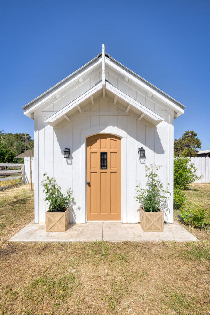 Small chapel with white walls and a brown door on grass
