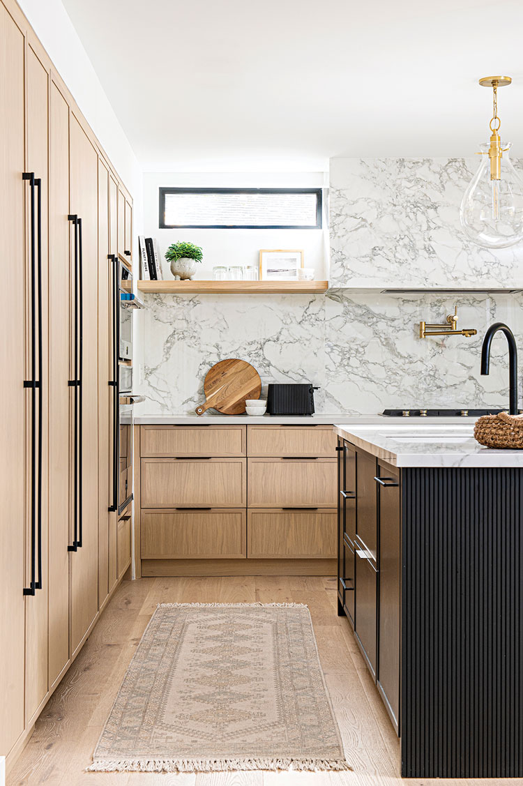 black kitchen island and marble backsplash with light wood cabinetry in Ontario home