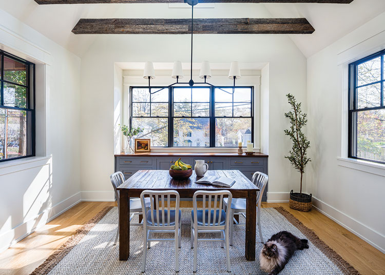 modern farmhouse dining room with exposed wood beams in ceiling and black chandelier and window frames