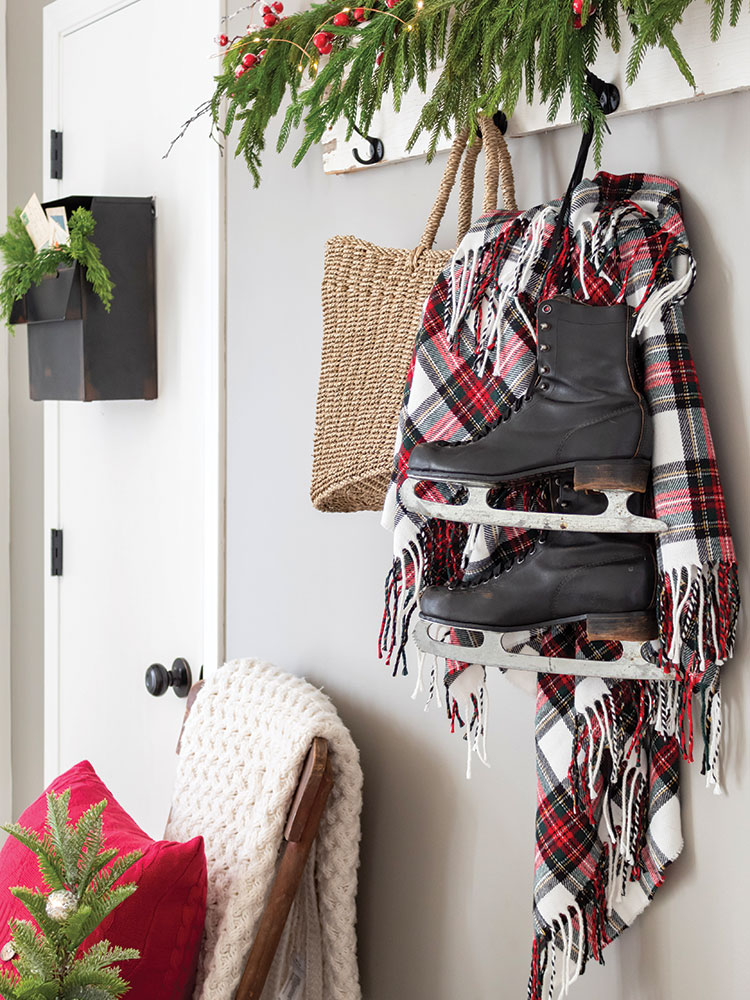 red and white plaid blanket and ice skates hang in entryway of holiday home