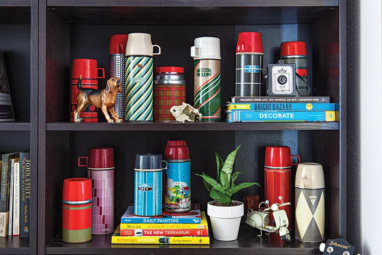 collection of vintage thermoses on black shelves