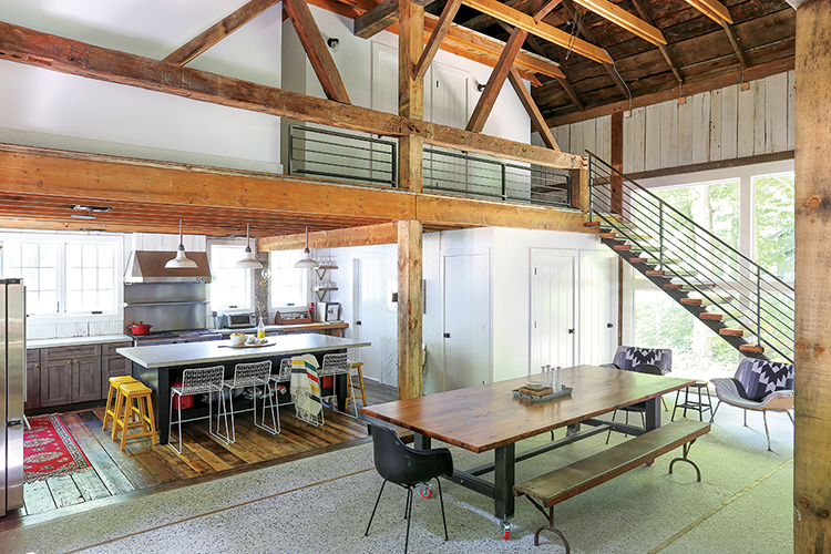 wide angle view of kitchen and dining room in renovated old barn with smart technology