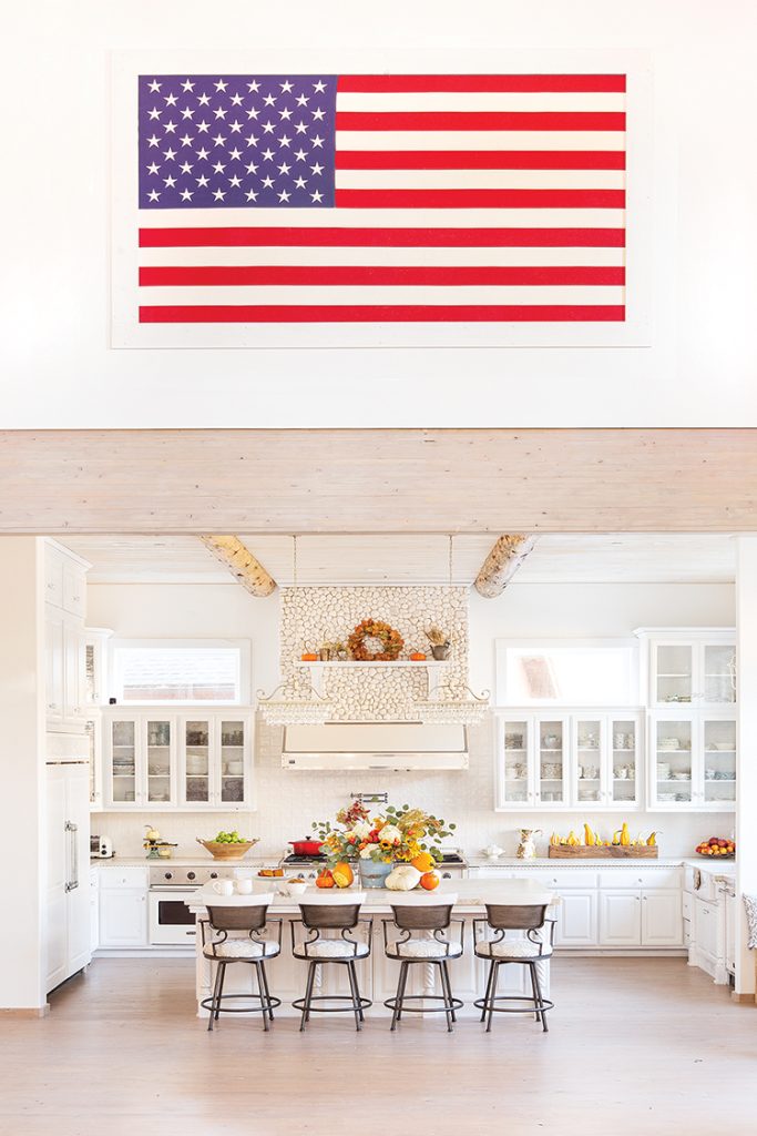 framed US flag above wall leading to the white kitchen in Big Bear farmhouse cabin