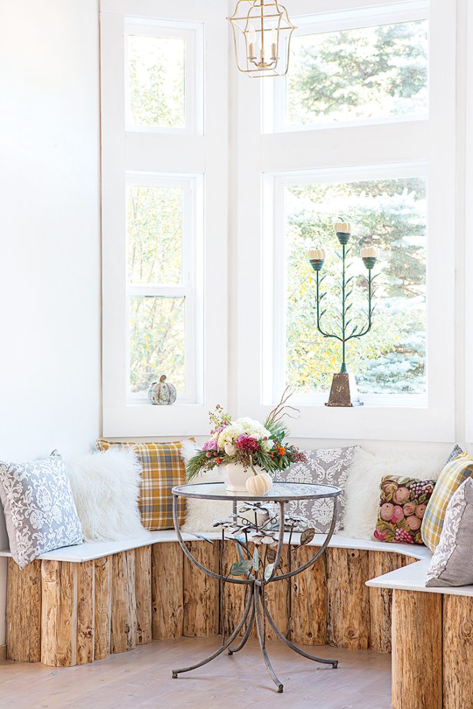 seating built from log stumps with colorful cushions and white decorative pumpkins