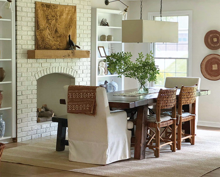 white dining room with neutral decor and vase of fresh leaves