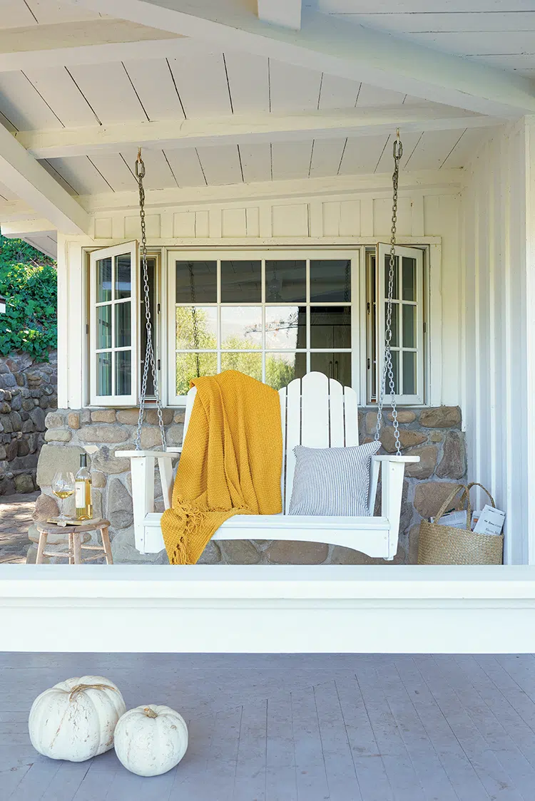 porch swing with mustard yellow throw and white pumpkins outside authentic farmhouse in Ojai