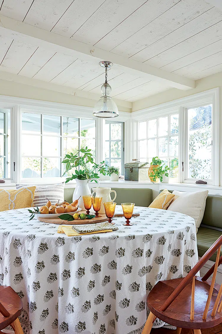 banquette in the breakfast room with yellow glassware and windows