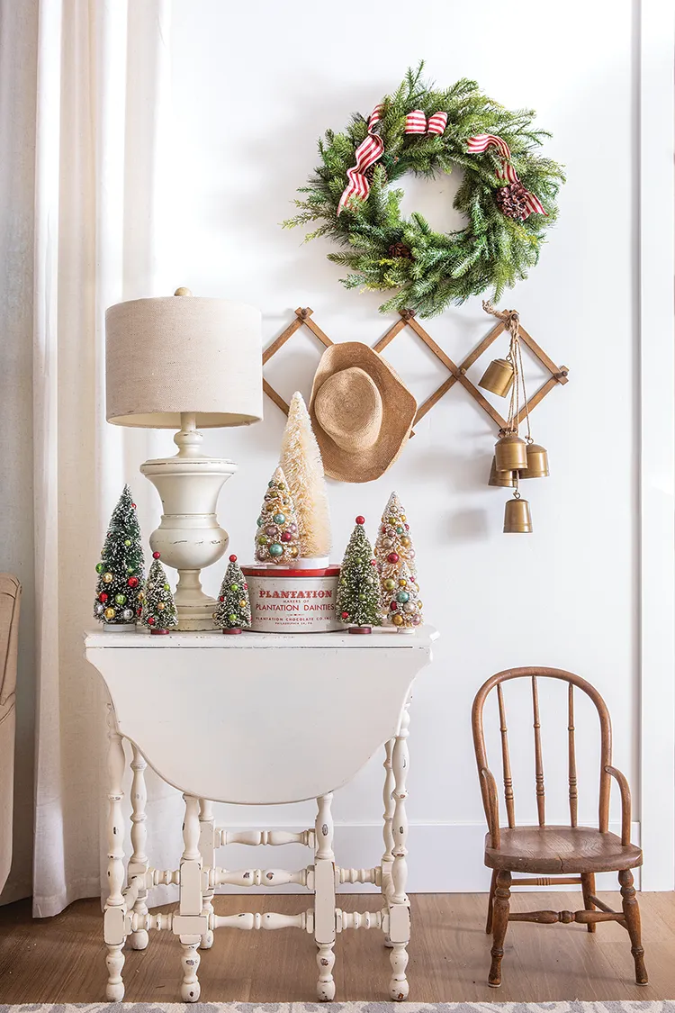 natural pine wreath with red and white ribbon and collection of vintage bottlebrush trees in home at Christmastime