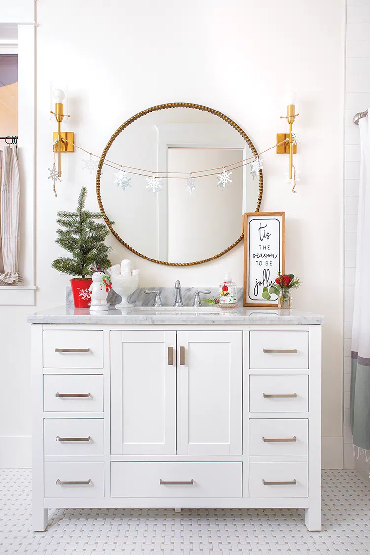 white bathroom with small potted tree and snowflake garland