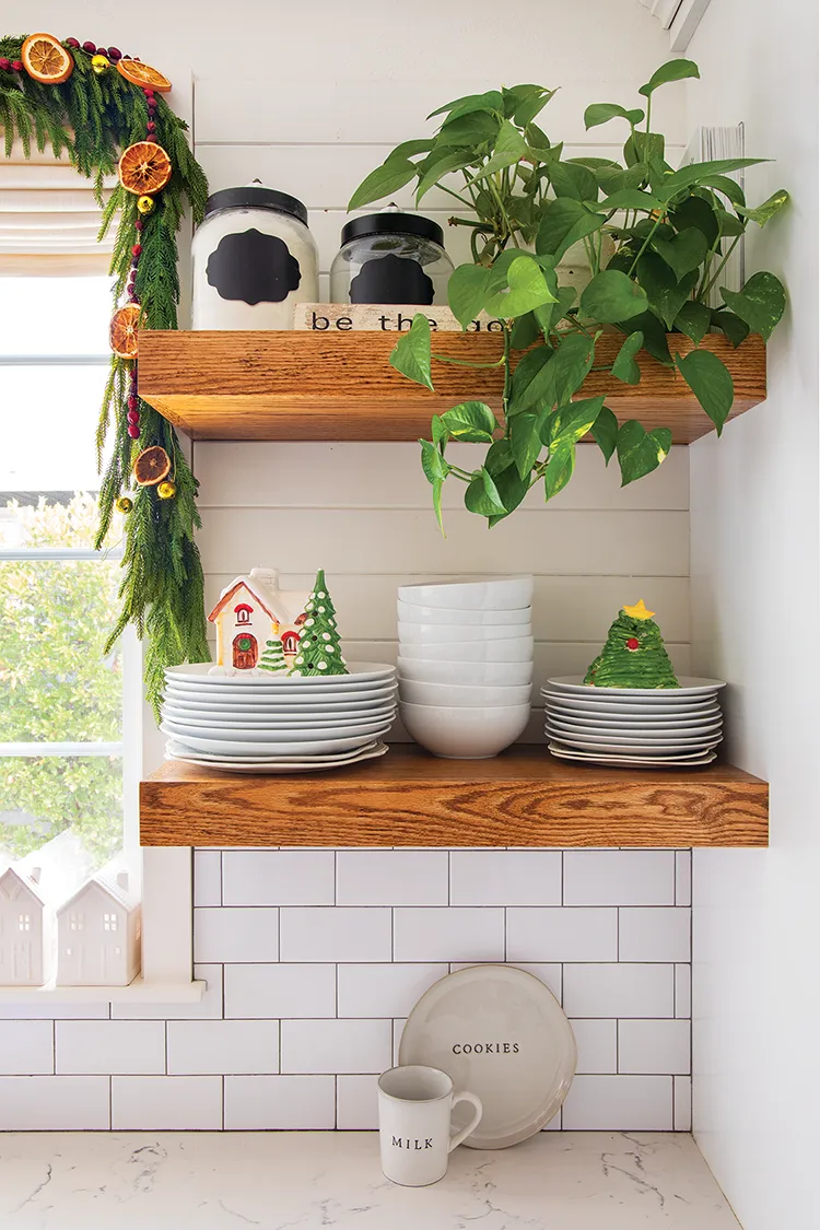 close up of farmhouse kitchen with exposed shelves and vintage Christmas figurines on stacks of plates