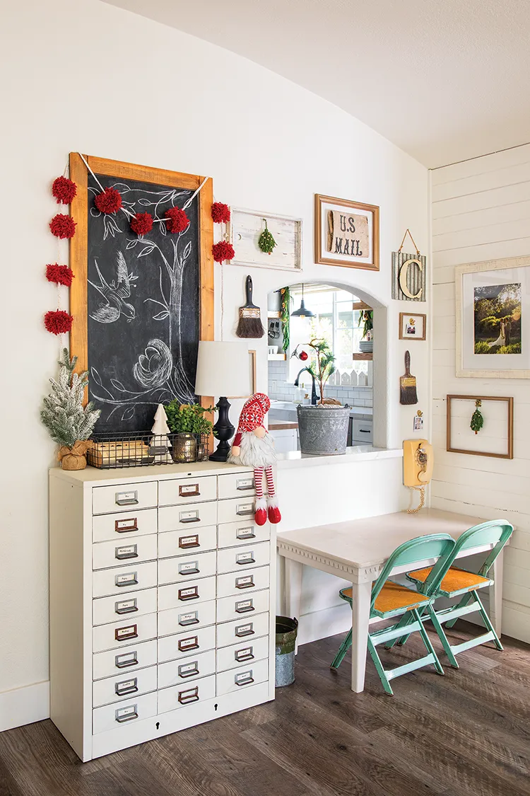 vintage apothecary chest with small Christmas trees and a red pom pom garland