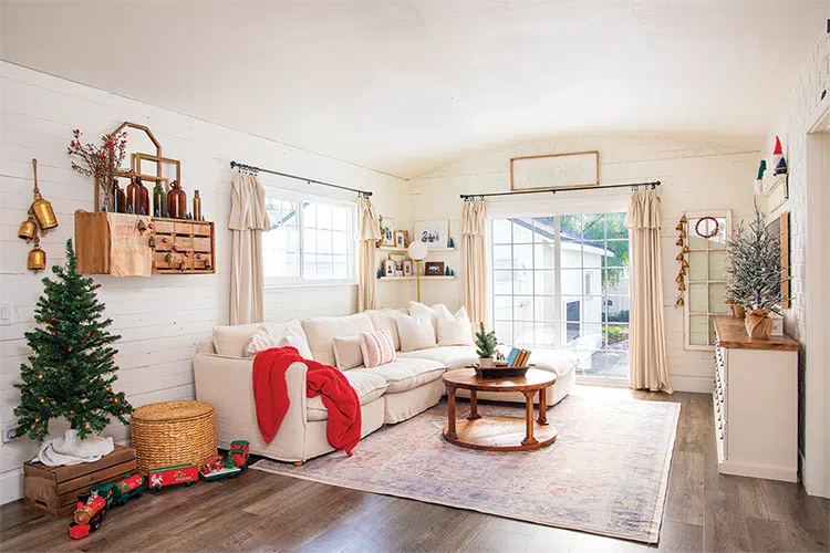 farmhouse style living room decorated for Christmas with small tree on wooden crate and red throw