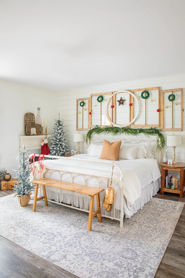 primary bedroom with small wreaths, pine garland and two small flocked Christmas trees