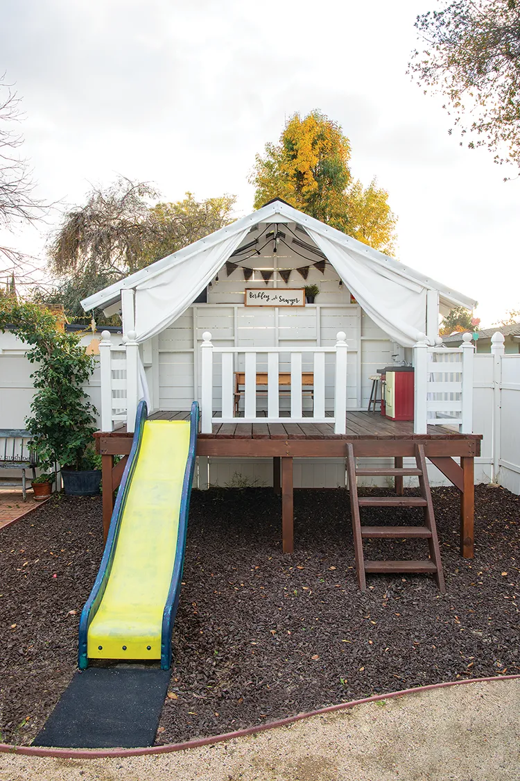 play set in backyard with slide and covered play house with pennants for decor