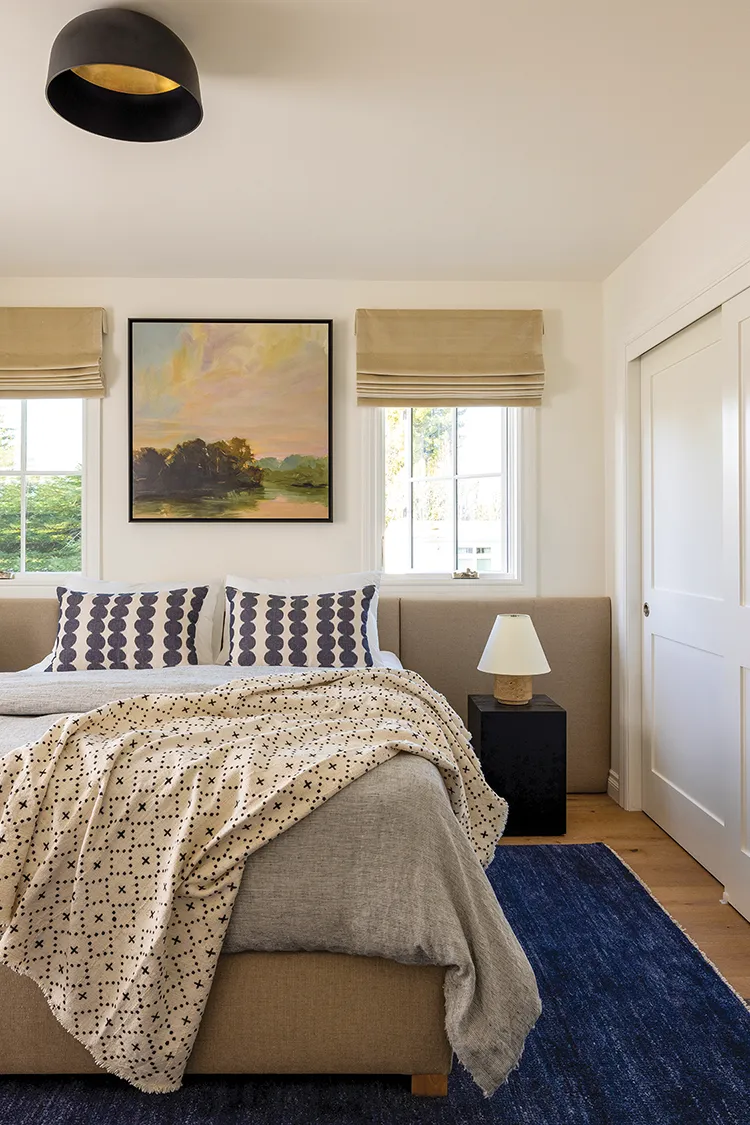 farmhouse bedroom with landscape painting and beige headboard