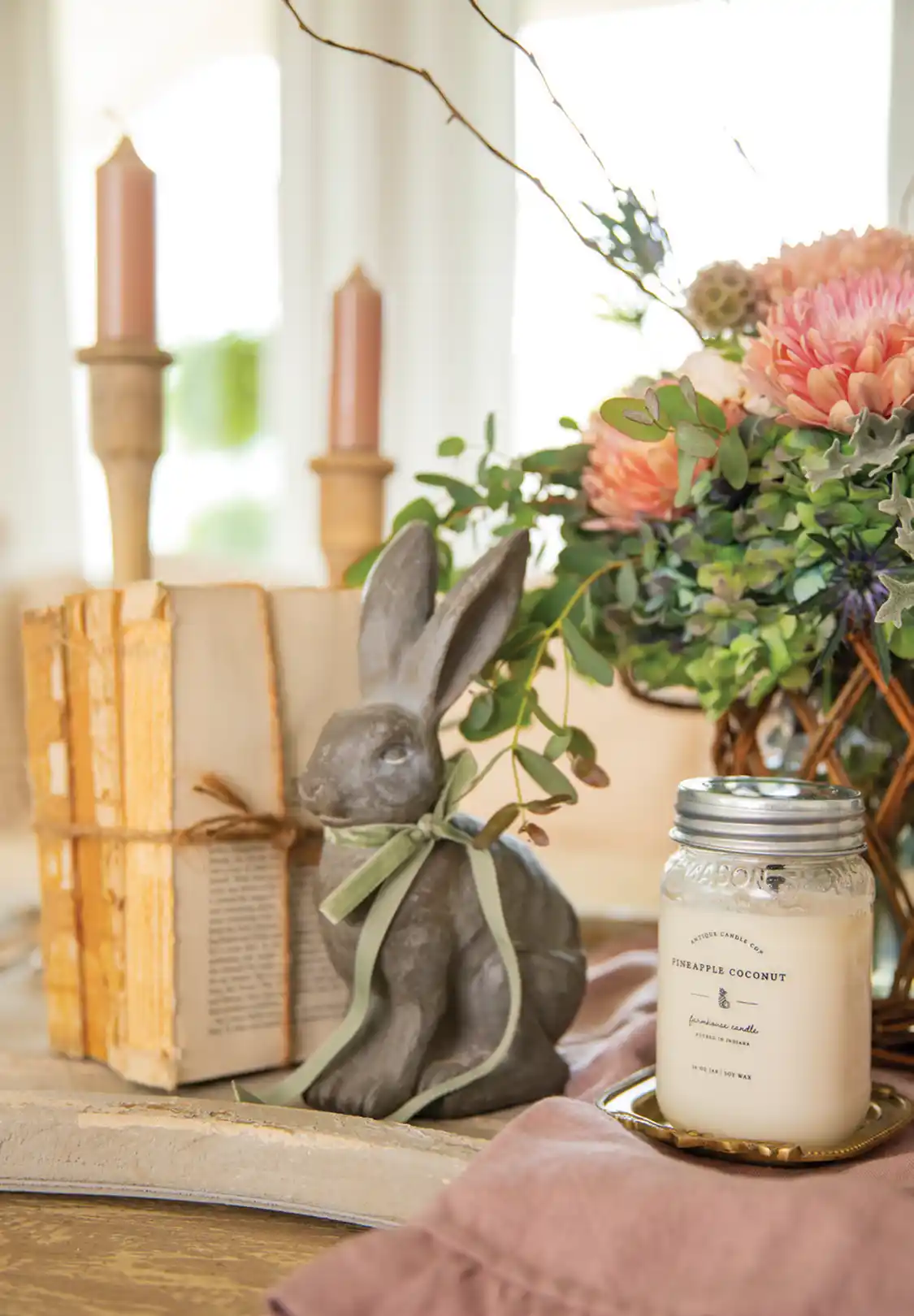 rabbit sculpture, vintage books and bouquet of flowers creates a spring vignette