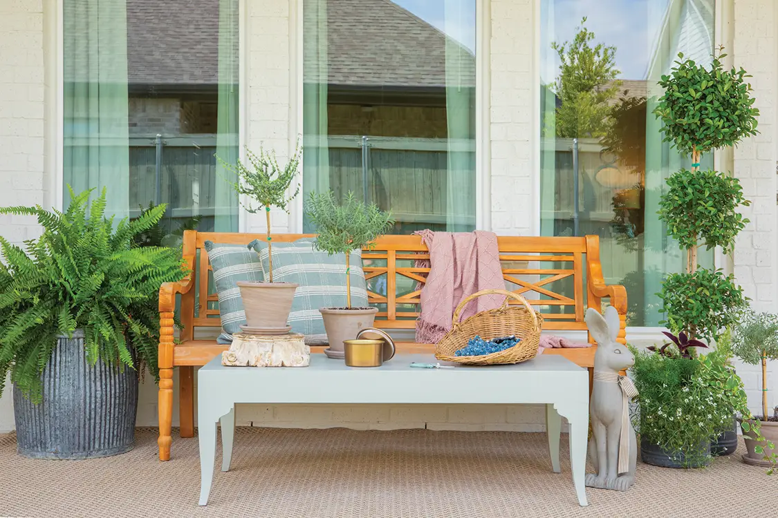 bench on patio with potted plants, flowerbasket and rabbit sculpture