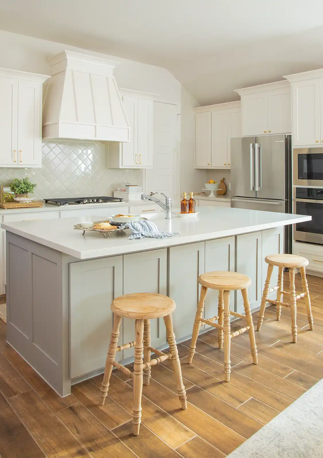 kitchen in new build farm cottage with pale green cabinetry in island and white cabinetry throughout