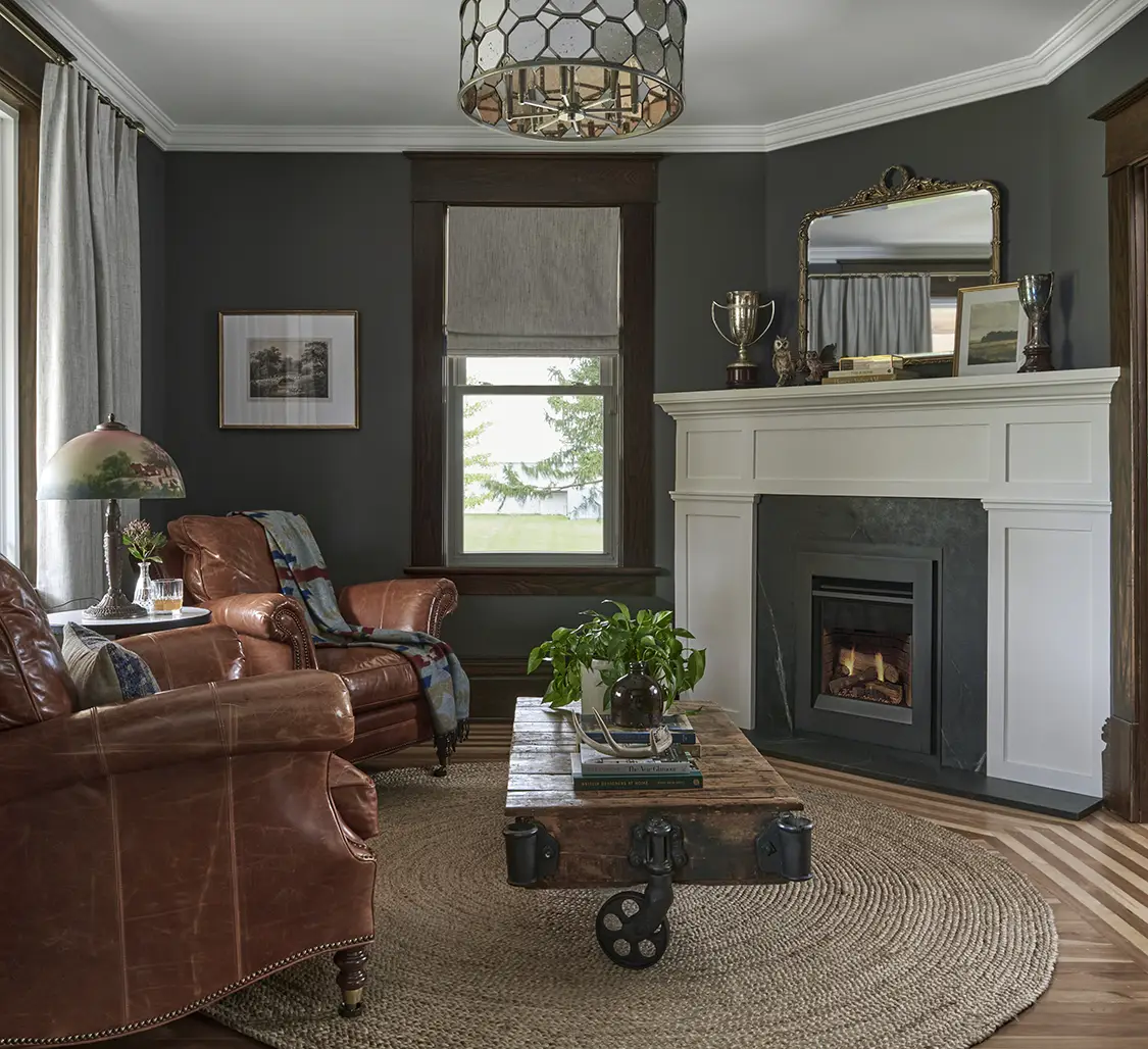 dark gray sitting room with brown leather sidechairs and fireplace