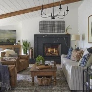 farmhouse living room with landscape paintings, leather side chairs and black marble fireplace surround