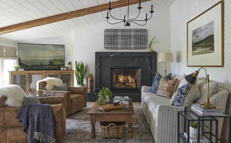 farmhouse living room with landscape paintings, leather side chairs and black marble fireplace surround