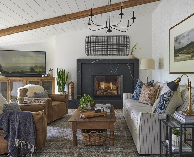 farmhouse living room with landscape paintings, leather side chairs and black marble fireplace surround