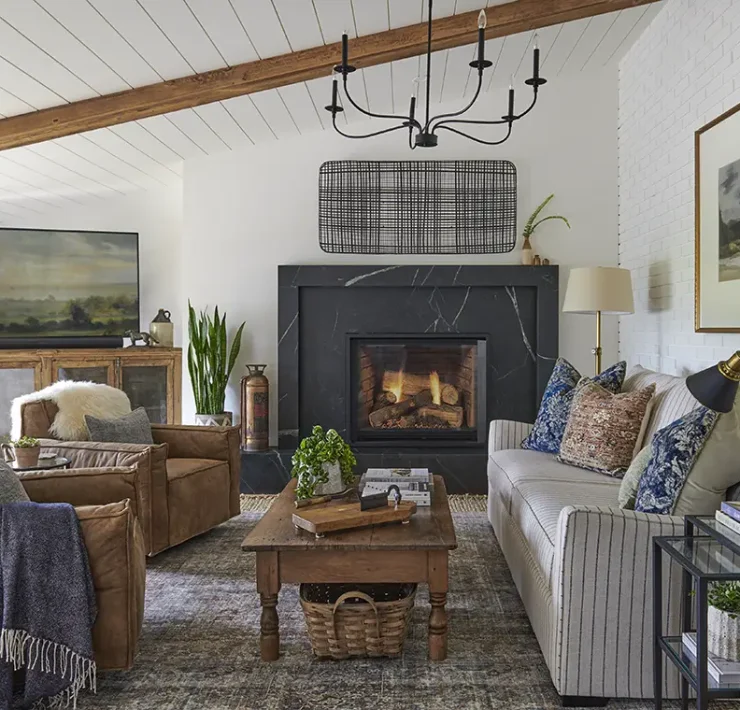 farmhouse living room with landscape paintings, leather side chairs and black marble fireplace surround