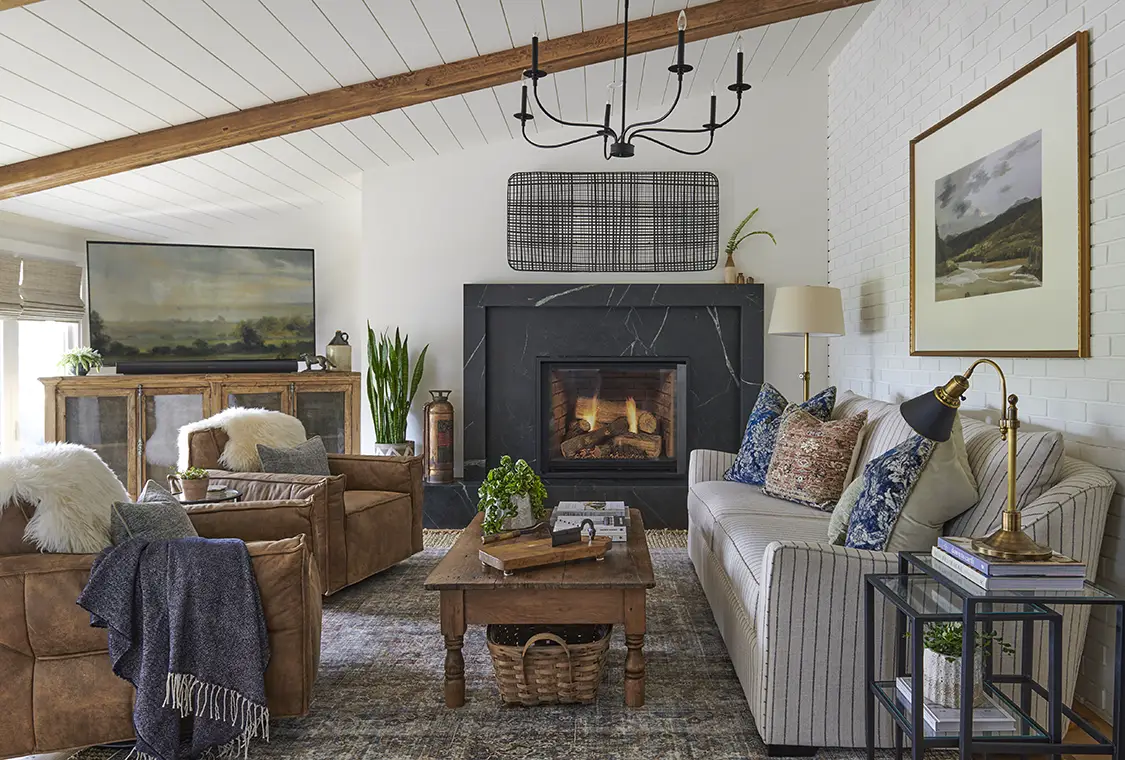 farmhouse living room with landscape paintings, leather side chairs and black marble fireplace surround